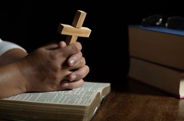 Women in religious concepts Hands praying to God while holding the cross symbol. Nun caught the cross in his hand. The human hand holds the holy cross and pray for God's blessings.